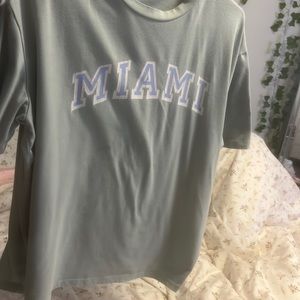 Greenish t-shirt that says Miami